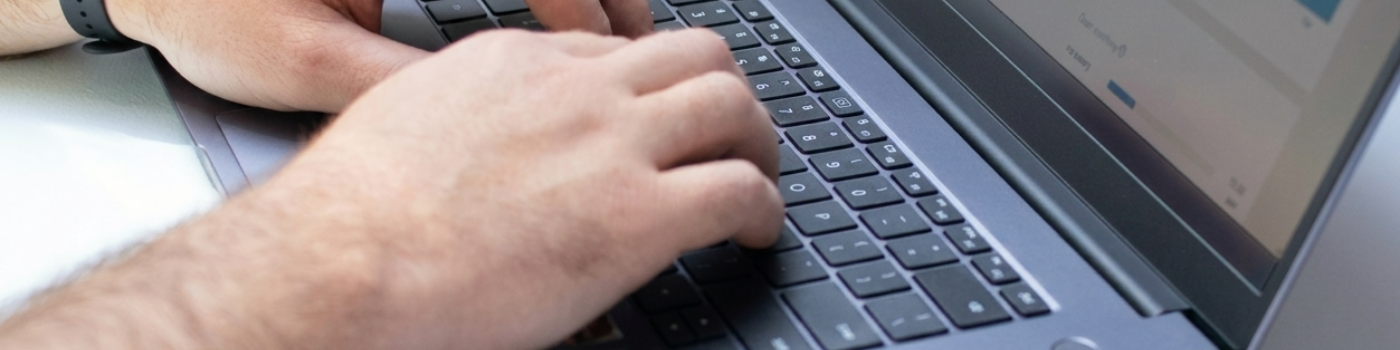 Personne en train de taper sur le clavier d'un ordinateur portable bleu foncé.